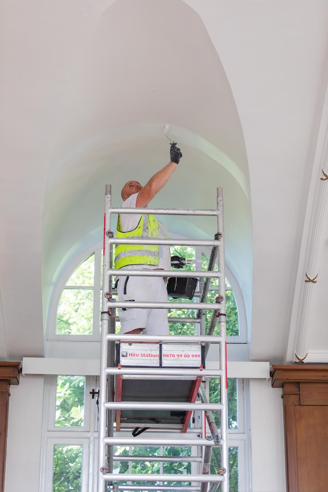Collab decorator working at height beneath an arched window