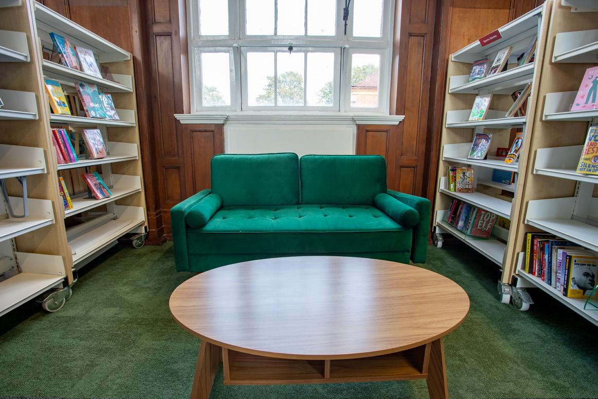 Refurbished library seating area with green sofa and timber table